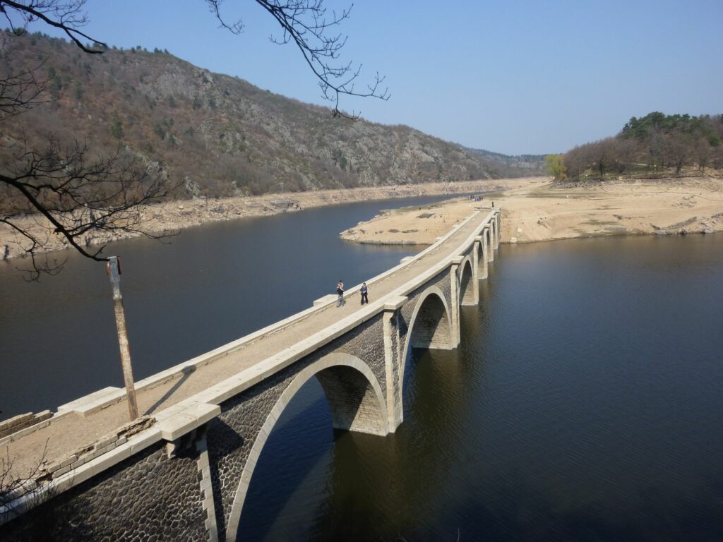 Pont en maçonnerie à arches traversant une retenue à bas niveau
