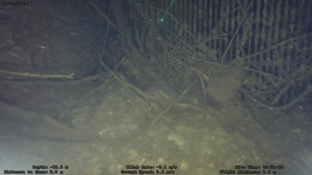 Vue caméra du ROV : grille de prise d'eau encombrée de branchages et de sédiments